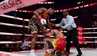 Anthony Joshua stands over a kneeling Jake Paul as the referee steps in during their heavyweight bout on December 19, 2025, at the Kaseya Center in Miami, Florida.