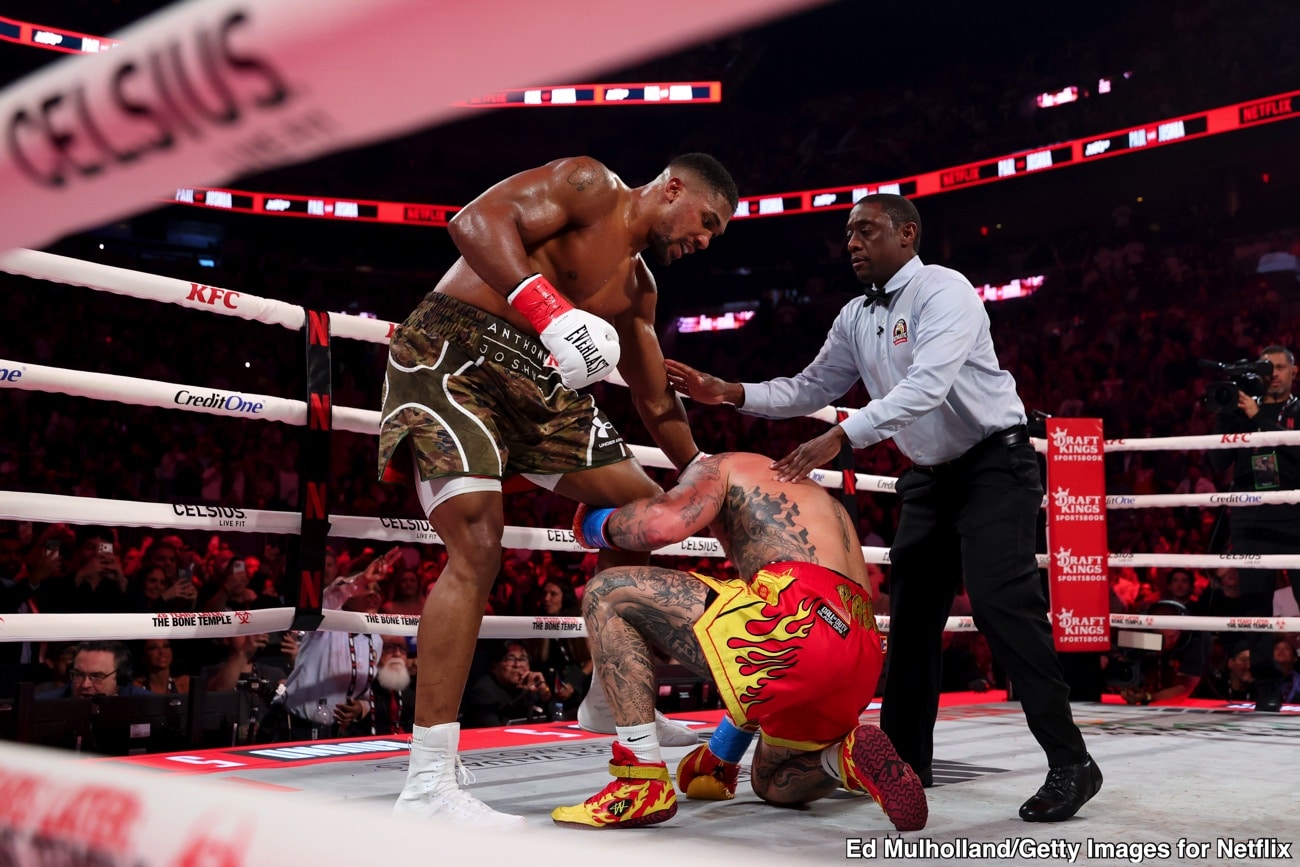 Anthony Joshua stands over a kneeling Jake Paul as the referee steps in during their heavyweight bout on December 19, 2025, at the Kaseya Center in Miami, Florida.