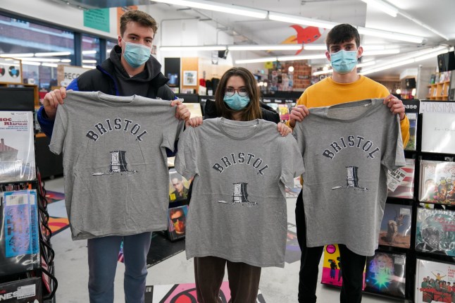 Customers in Rough Trade in Bristol, with a T-shirt designed by street artist Banksy being sold to support four people facing trial accused of criminal damage in relation to the toppling of a statue of slave trader Edward Colston. Picture date: Saturday December 11, 2021. PA Photo. The anonymous artist posted on Instagram pictures of limited edition grey souvenir T-shirts which will go on sale on Saturday in Bristol. The shirts have a picture of Colston's empty plinth with a rope hanging off, with debris and a discarded sign nearby and the BRISTOL written above. See PA story ARTS Banksy. Photo credit should read: Jacob King/PA Wire