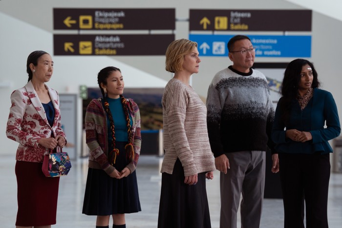 Sharon Gee, Darinka Arones, Rhea Seehorn, Amarburen Sanjid and Menik Gooneratne in Pluribus, stood together in an airport looking at something off screen.