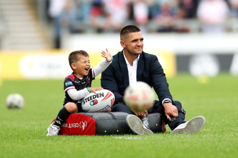 SALFORD, ENGLAND - JUNE 15: Jayden Nikorima of Salford Red Devils and his son Mali watch the warm up prior to the Betfred Super League match between Salford Red Devils and St.Helens at Salford Community Stadium on June 15, 2025 in Salford, England. (Photo by Jess Hornby/Getty Images)