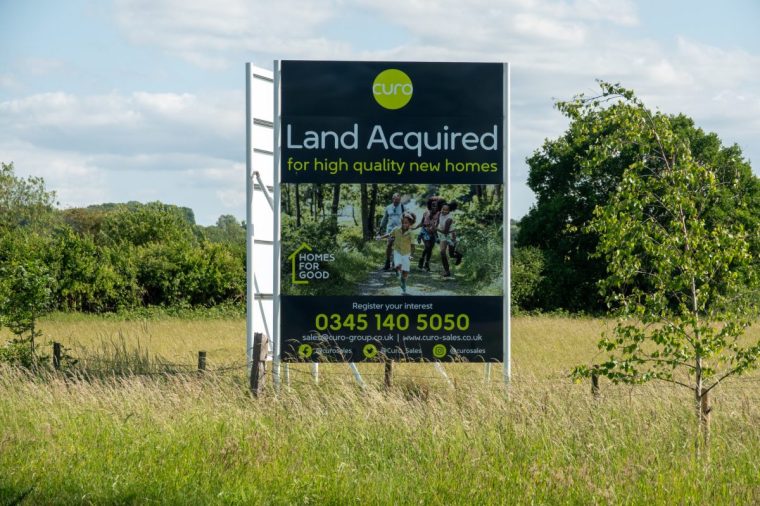 KEYNSHAM, UNITED KINGDOM - JUNE 03: A developers sign advertises new houses that will be constructed on what was previously green belt agricultural land on June 3, 2025 in Somerset, England. The new Labour government has proposed new planning and infrastructure laws designed to help unlock economic growth and deliver much-needed new housing and wider developments such as renewable energy projects. (Photo by Anna Barclay/Getty Images)