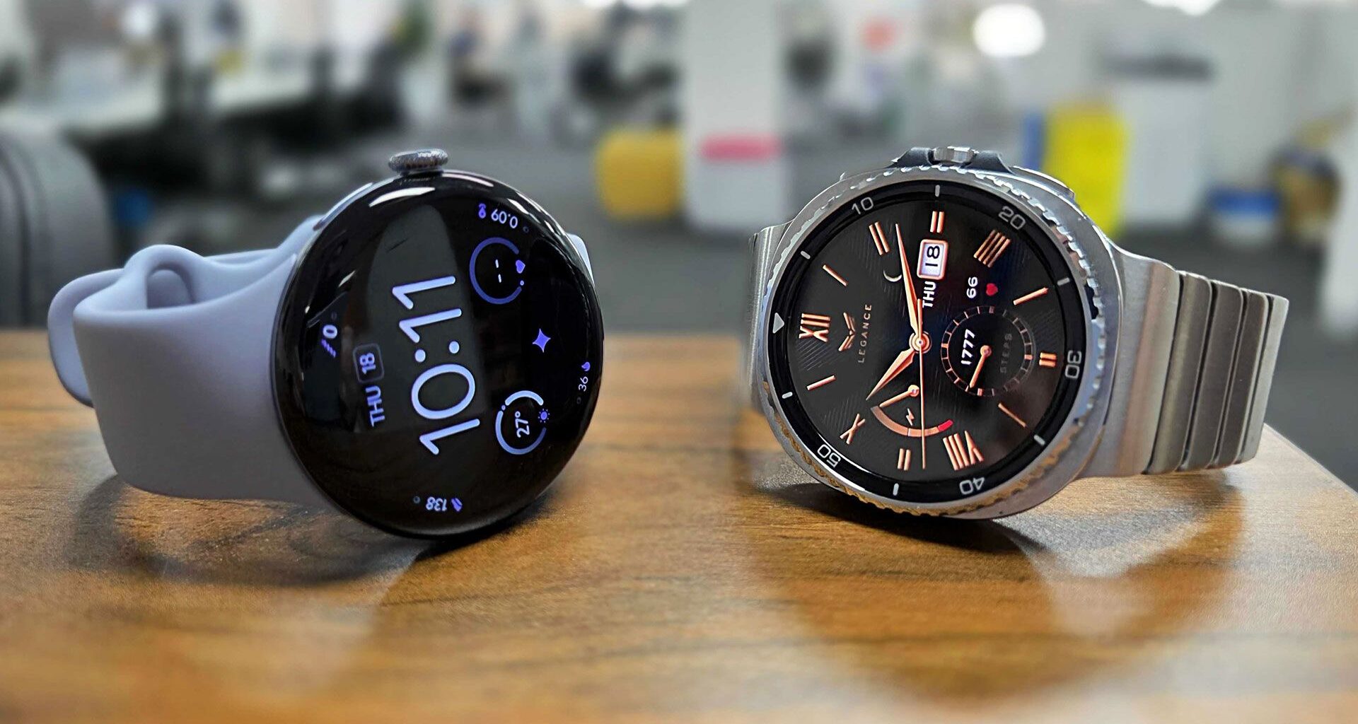 Google Pixel Watch 4 and Samsung Galaxy Watch 8 Classic placed side by side on bench top