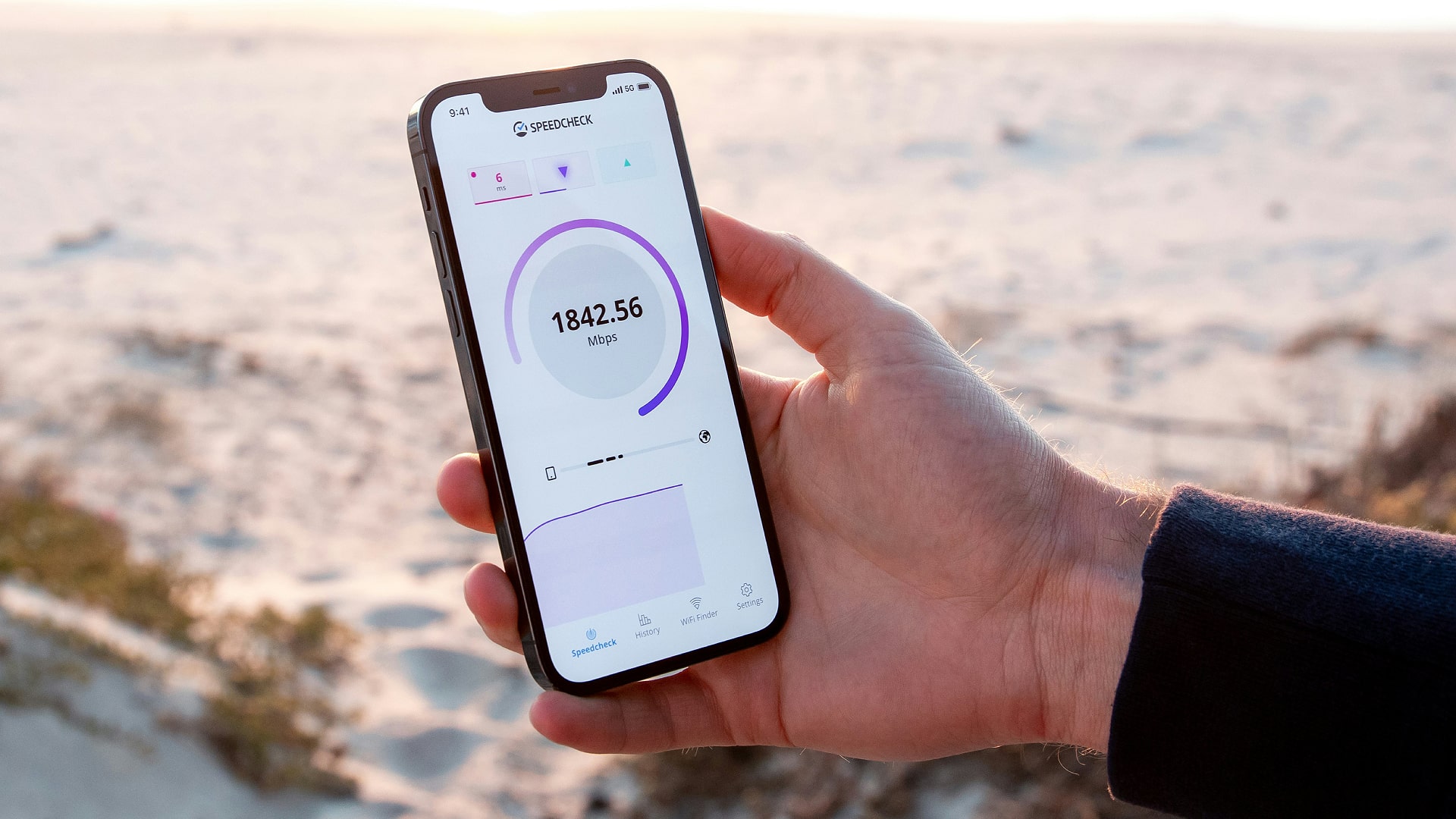 A person holds an iPhone while it is performing a 5G speed test.