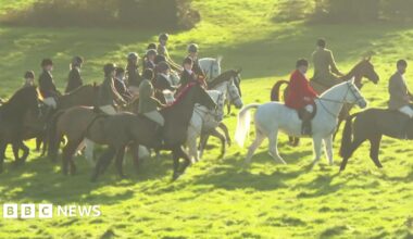 A group of people riding horses through a grassy field.
