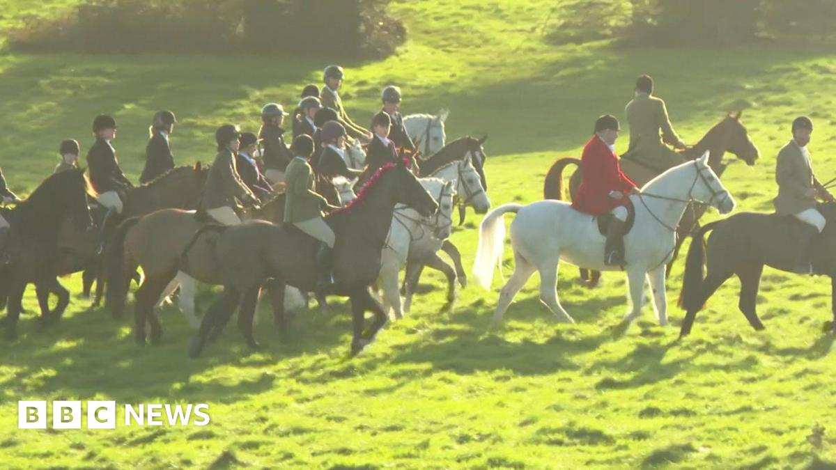A group of people riding horses through a grassy field.