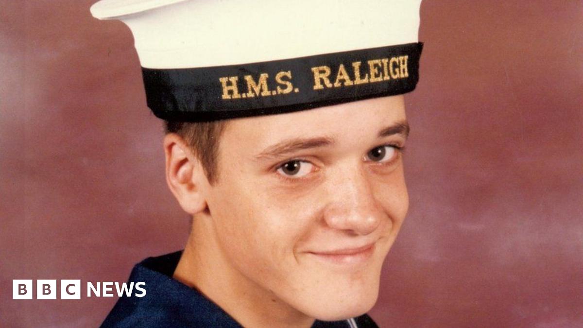 Simon Parkes smiles at the camera in a portrait photo. He wears a navy uniform with an HMS Raleigh cap
