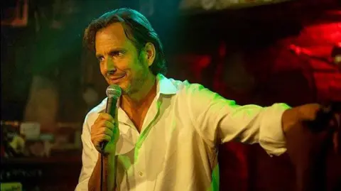 Searchlight Pictures Will Arnett performing on stage holding a microphone in Is This Thing On?