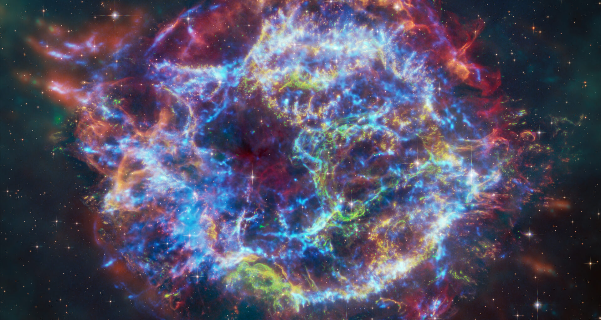 This image of Cassiopeia A resembles a disk of electric light with red clouds, glowing white streaks, red and orange flames, and an area near the center of the remnant resembling a somewhat circular region of green lightning. X-rays from Chandra are blue and reveal hot gas, mostly from supernova debris from the destroyed star, and include elements like silicon and iron. X-rays are also present as thin arcs in the outer regions of the remnant. Infrared data from Webb is red, green, and blue. Webb highlights infrared emission from dust that is warmed up because it is embedded in the hot gas seen by Chandra, and from much cooler supernova debris. Hubble data shows a multitude of stars that permeate the field of view.