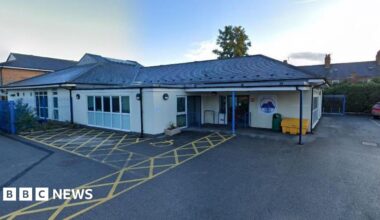 A single-storey building stands at the end of a large tarmacked area.