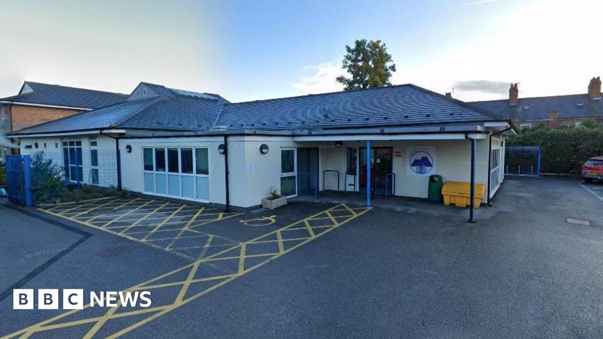 A single-storey building stands at the end of a large tarmacked area.