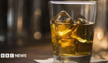 A glass tumbler filled with whisky and ice.