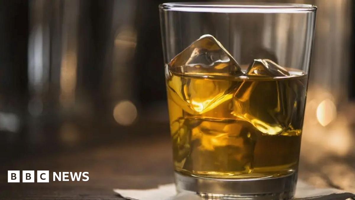 A glass tumbler filled with whisky and ice.