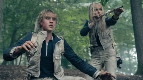Murray Close/Lionsgate Joseph Zada as Haymitch Abernathy and McKenna Grace as Maysilee Donner in a forest scene from the film 