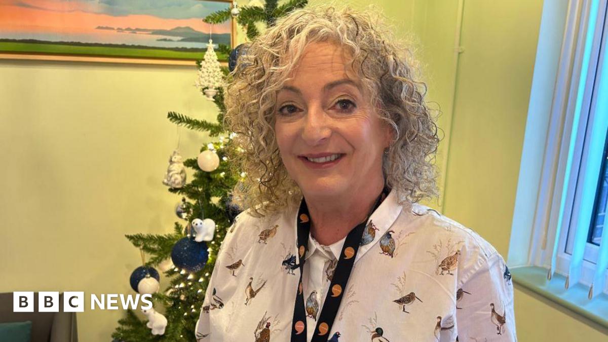 A woman with curly hair smiles at the camera