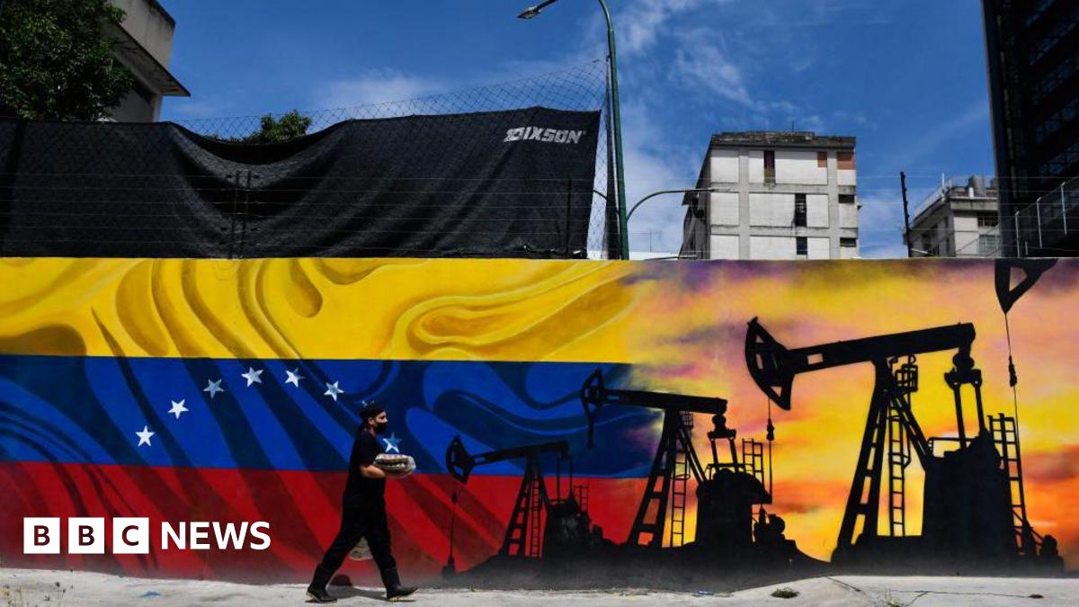 A man wearing a face masks walks past a mural depicting an oil pump and the Venezuelan flag in a street of Caracas, on May 26, 2022. (Photo by Federico PARRA / AFP)