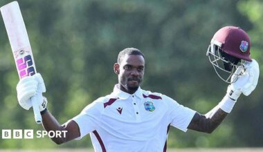 Justin Greaves holds his bat and helmet aloft after reaching 200