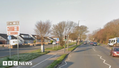 A red car drives alongside Westgate in Morecambe, with a lorry behind about to turn into the road