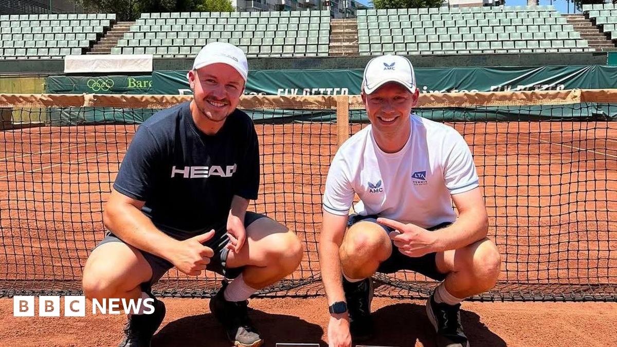 Matt Grover and Ross Cudmore on a clay court in Barcelona smiling by the net.