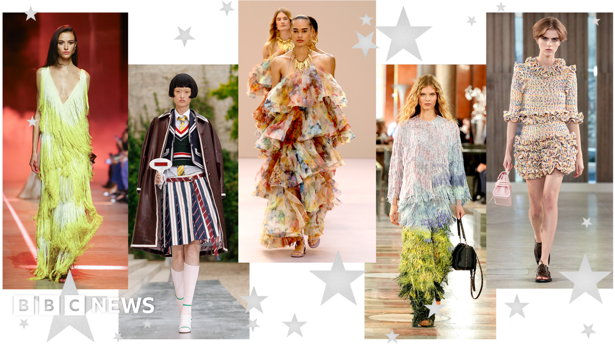 Five pictures of models walking down the catwalk. The first is in a fringed green dress with low v-neck; the second wears a striped pleated midi skirt, shirt and tie, tank top and blazer with brown leather coat draped over her shoulders; the third wears an off-shoulder, ruffled multicolour dress; the fourth wears a head-to-toe tasseled outfit with ombre blue and green effect; the fifth wears a ruffled mulitcolour mini skirt with ruffled three-quarter length sleeve top