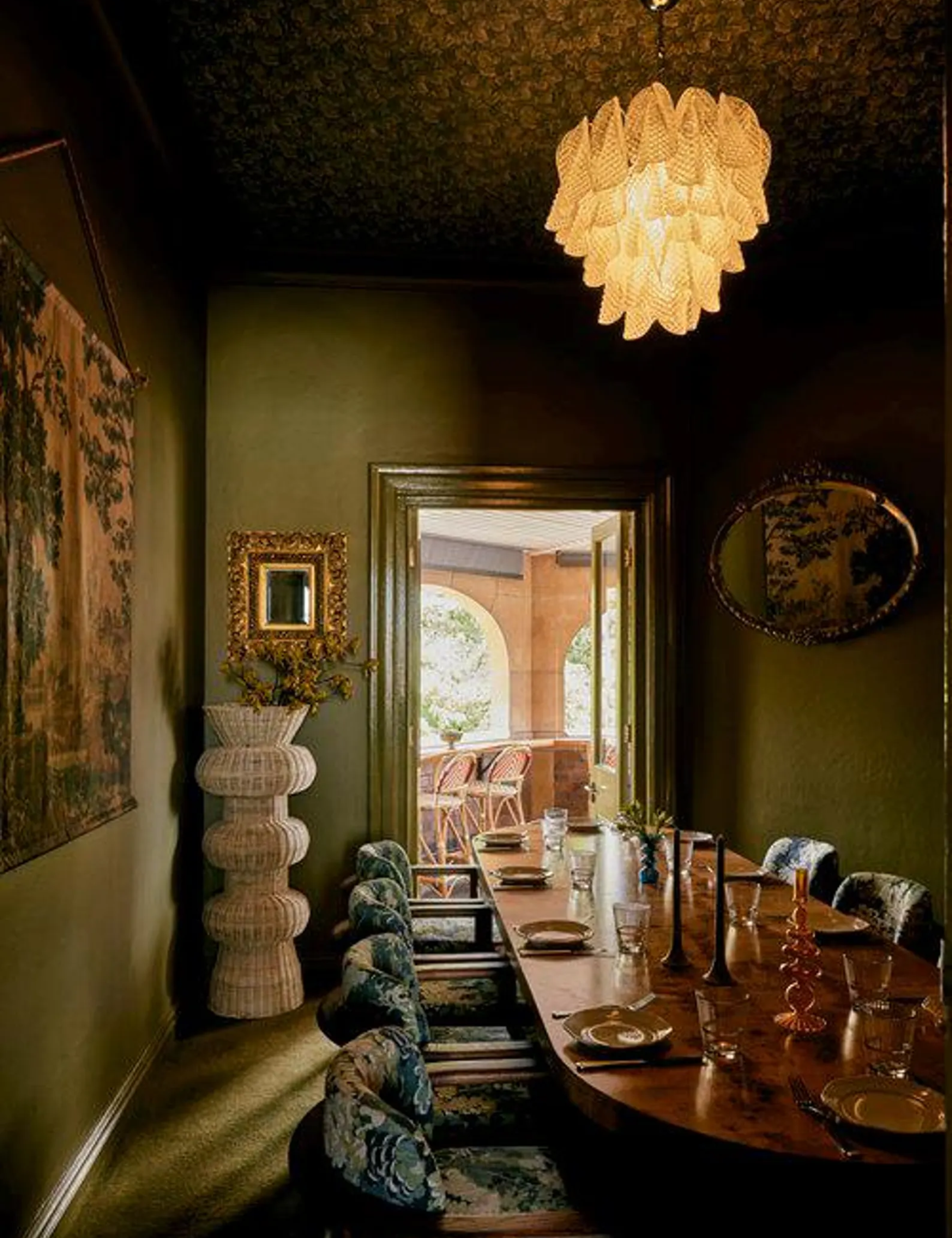 Verdant green dining room featuring a multi-tier chandelier and a vintage-inspired wall tapestry