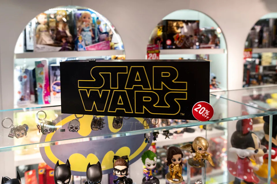 Store display featuring collectibles, including keychains and figurines, with a prominent "Star Wars" sign and a 20% off discount tag