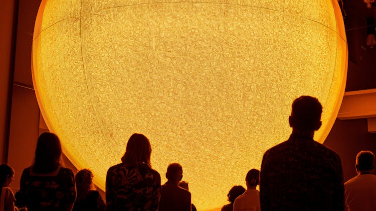 A crowd in front of an artificial sun.