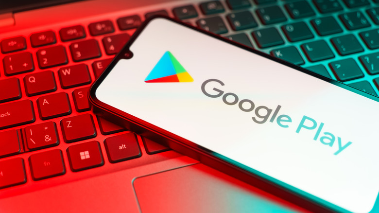 A phone with the Google Play logo on top of a laptop keyboard.