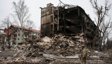 A Ukrainian police officer in camouflage gear walks past the rubble of heavily damaged buildings in Dobropillia.