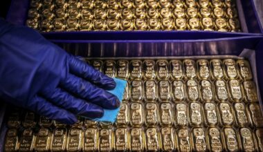 A worker wearing blue gloves polishes rows of gold bullion bars at the ABC Refinery.