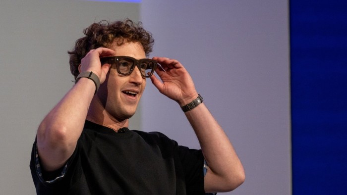 Mark Zuckerberg puts on Meta Ray-Ban Display AI glasses, smiling, during a presentation at the Meta Connect event.