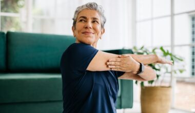 Woman doing yoga for strength work, sitting on living room floor and stretching