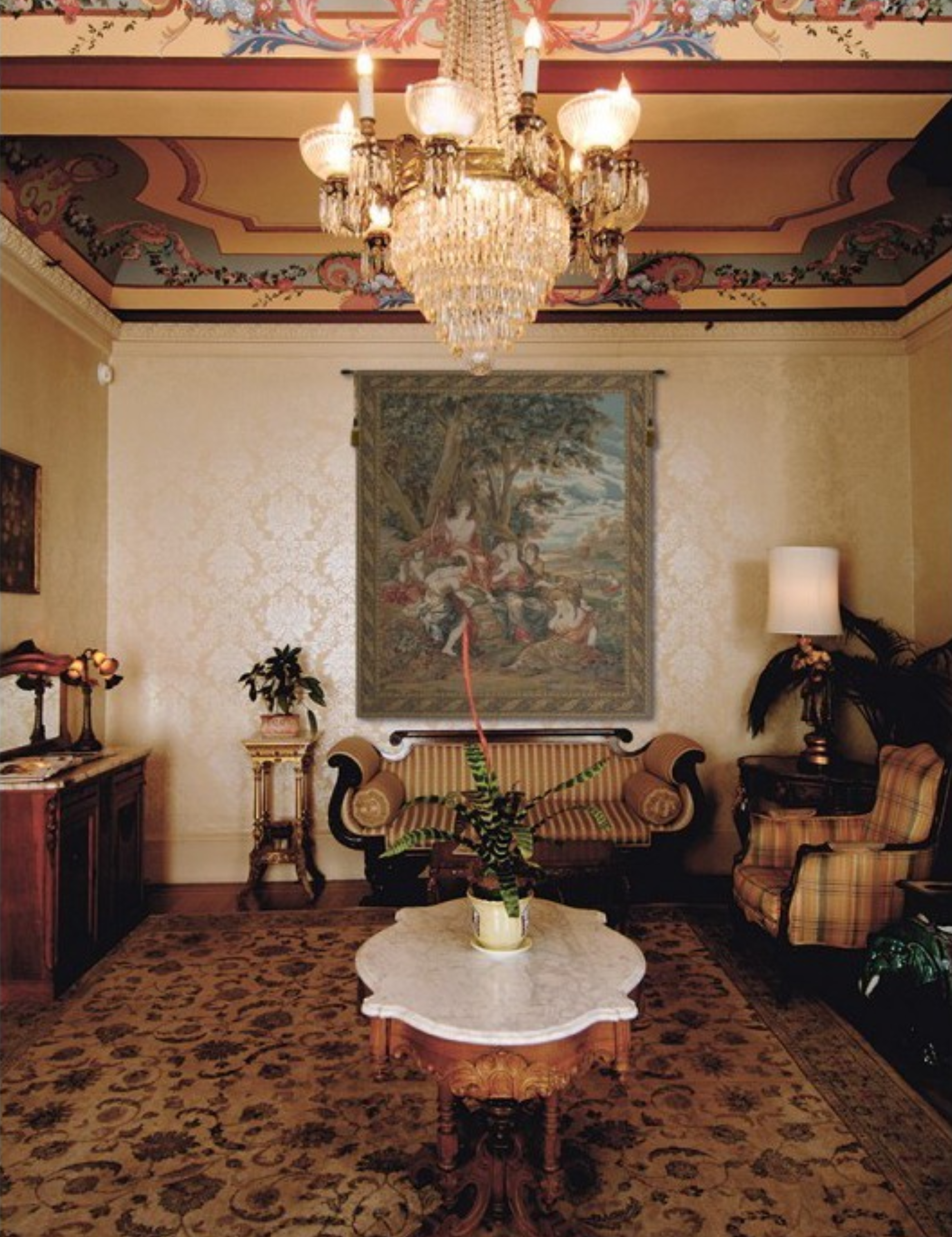 Ornate sitting room featuring a crystal chandelier and a large wall tapestry