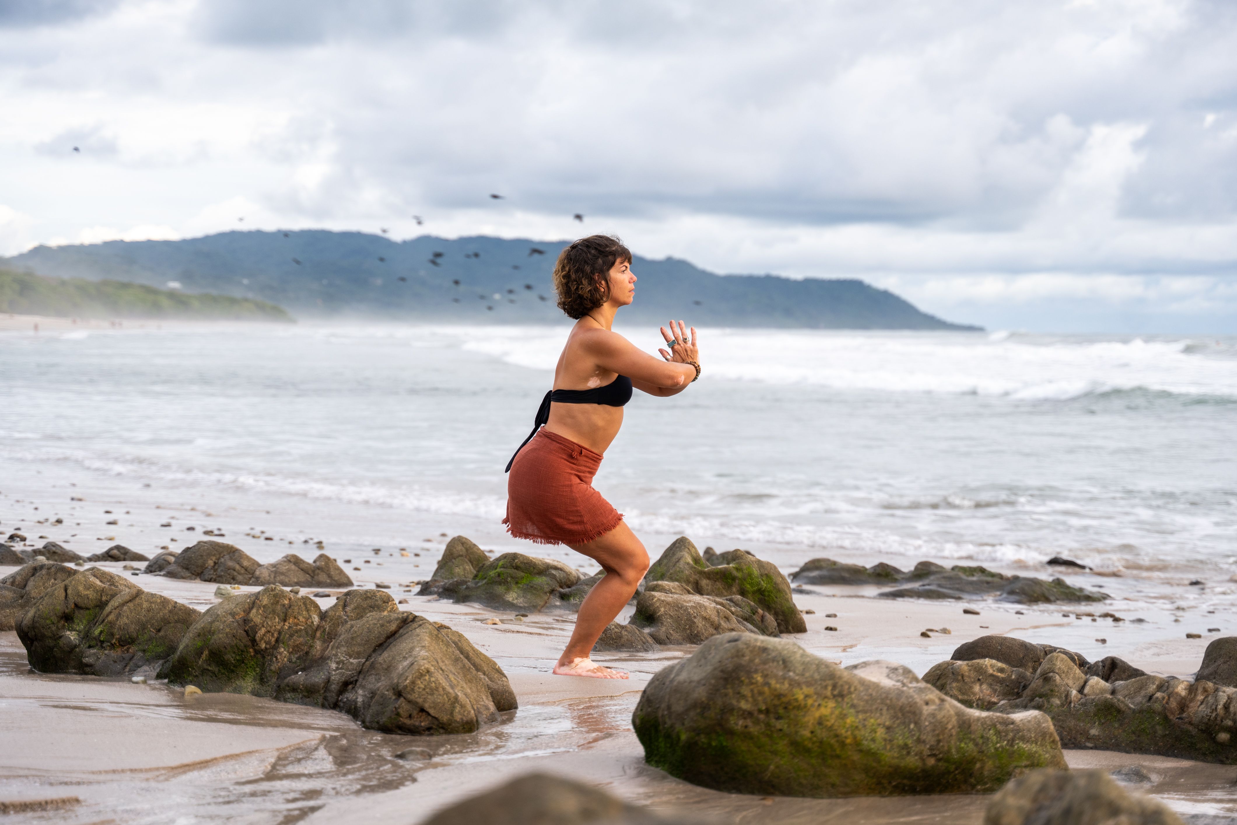 woman on beach doing standing yoga