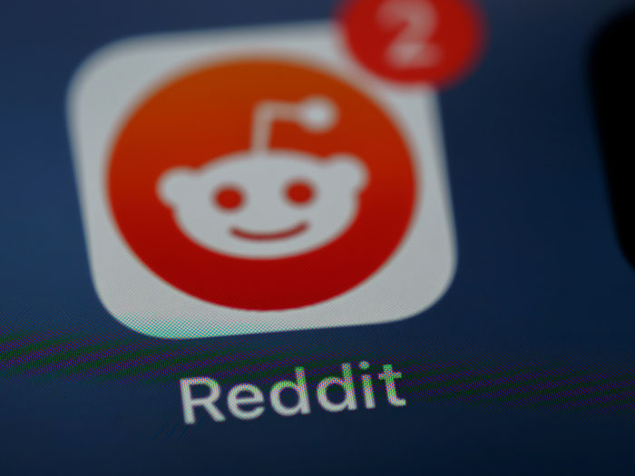Reddit app icon on a smartphone screen with notification badge, representing AI industry discussions and insights.