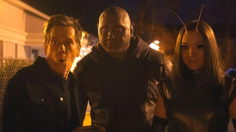 Kevin Bacon, Dave Bautista's Drax, and Pom Klementieff's Mantis standing side by side and looking happy on The Guardians of the Galaxy Holiday Special
