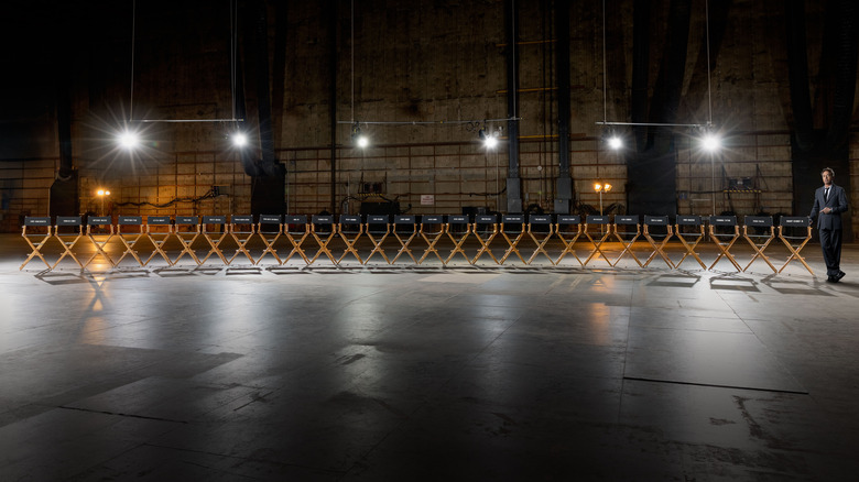 Robert Downey, Jr. standing in a warehouse next to a row of empty director's chairs in a promotional stunt for Avengers: Doomsday