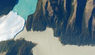 Astronaut photo of the point where a glacier, green river and blue lake meet in a valley system in Patagonia