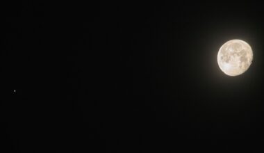 A near-full moon shines to the right of an image of the black night sky, while a small point of light representing Jupiter can be seen to the left of the image.