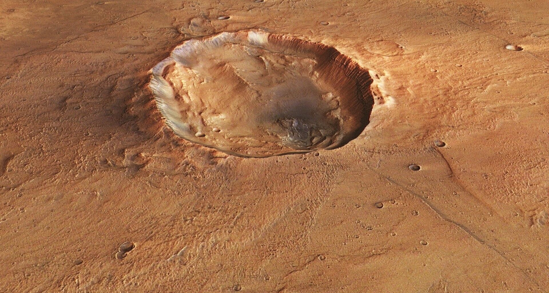 A photo of the surface of Mars from space, with a large crater seen in its reddish brownish surface