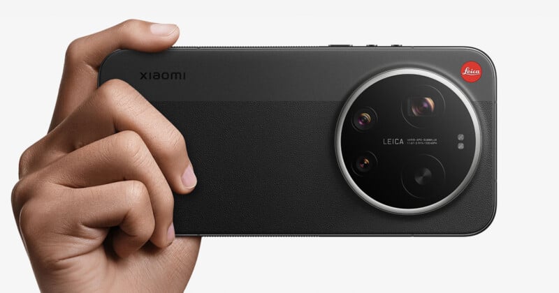 A hand holds a black Xiaomi smartphone horizontally, showcasing its large circular Leica-branded rear camera module with multiple lenses and a red Leica logo.