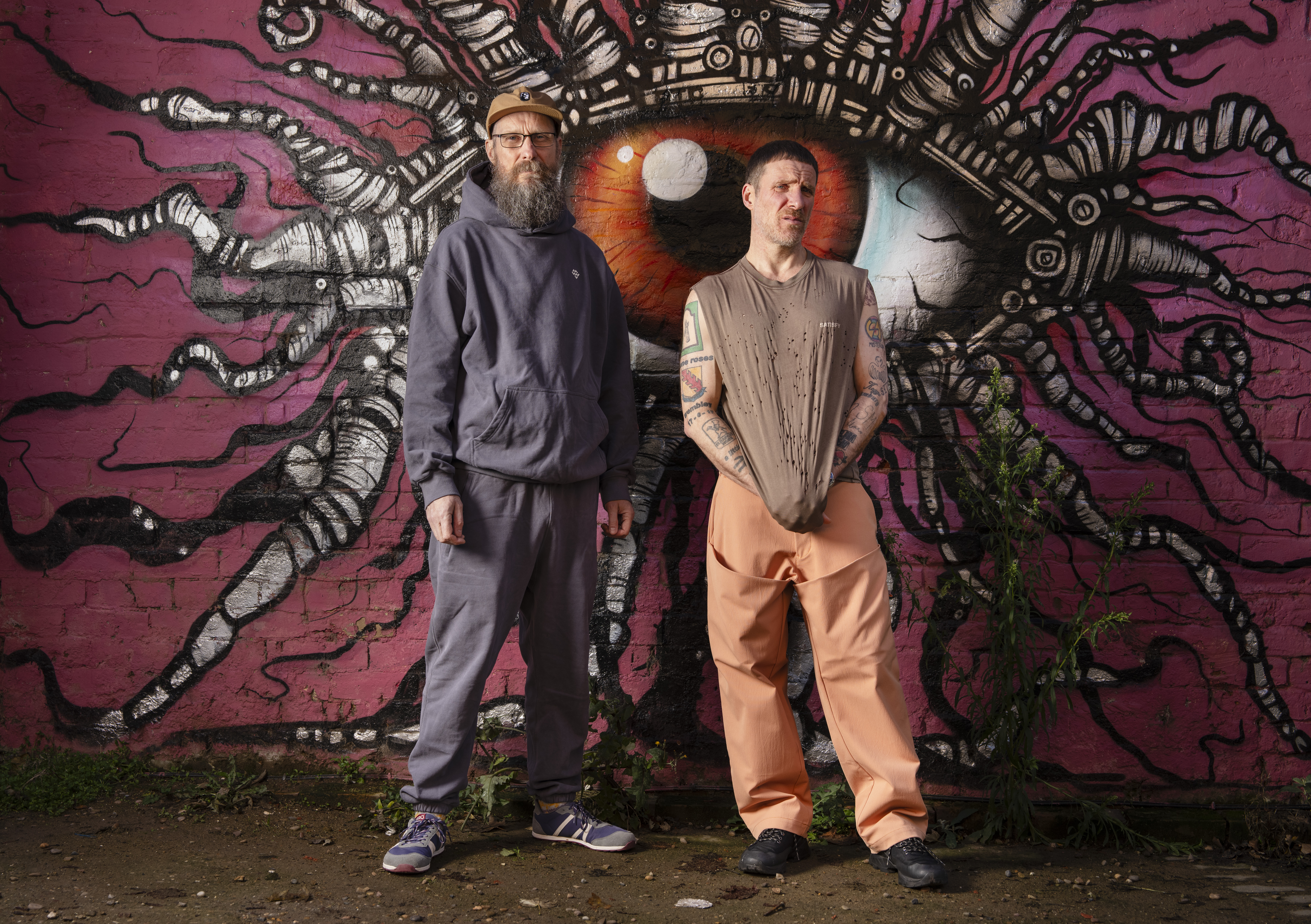 The Sleaford Mods, Andrew Fearn and Jason Williamson, standing in front of a mural.