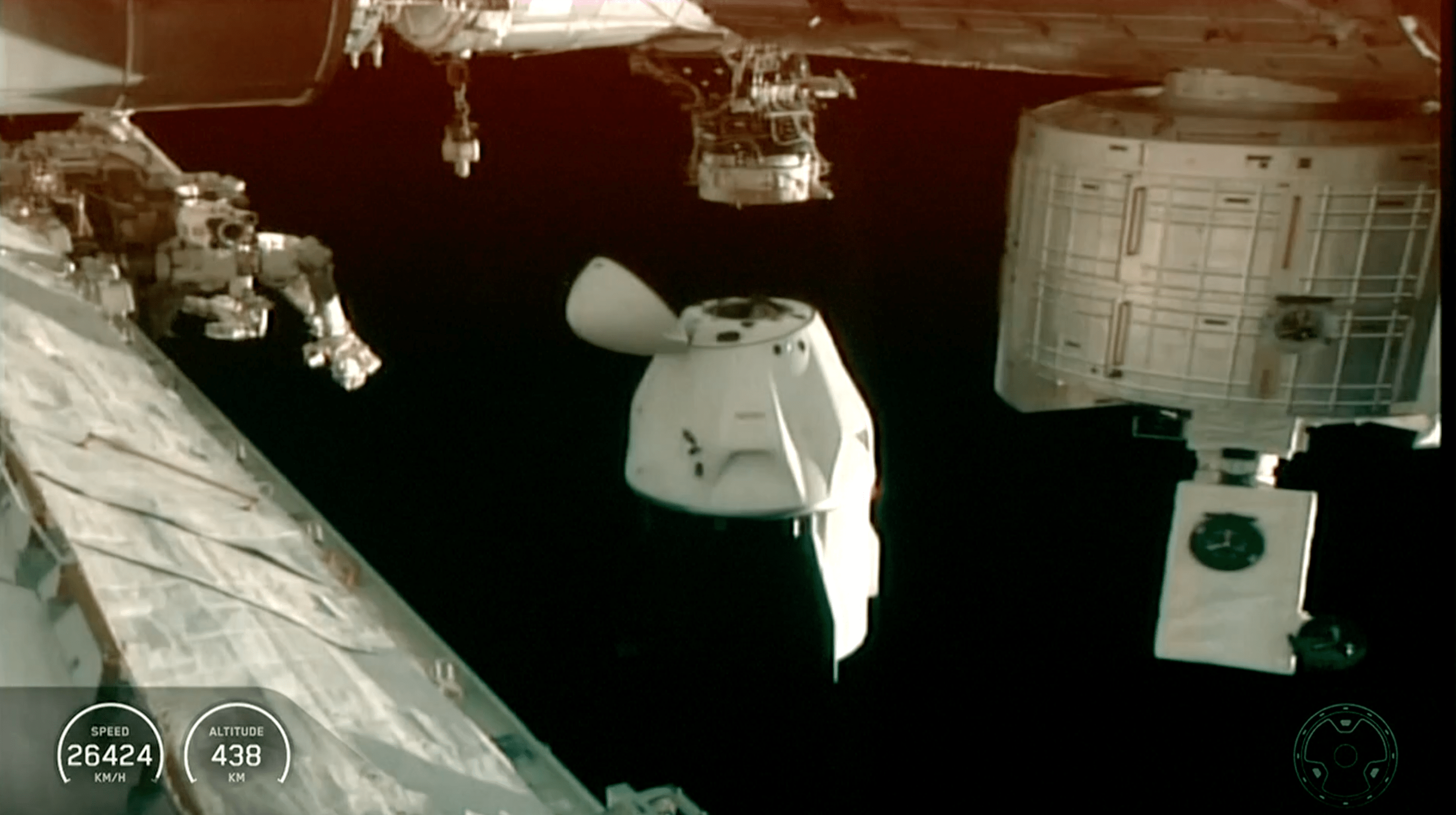 A Dragon spacecraft approaches the International Space Station, with the Earth in the background, showing a speed of 26424 km/h and an altitude of 438 km.