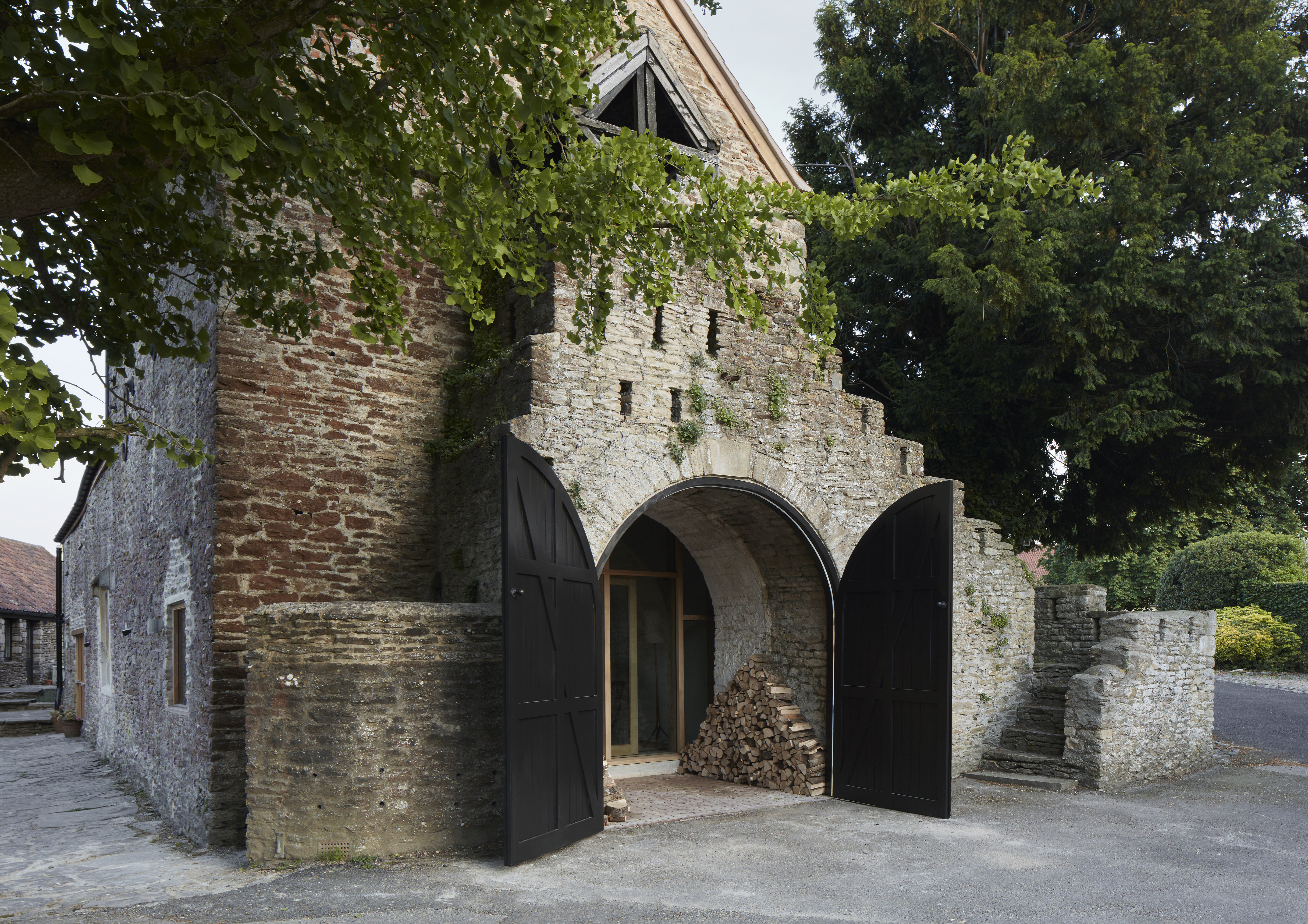 Wool Hall, a large stone barn with an arched entrance framed by open black doors.