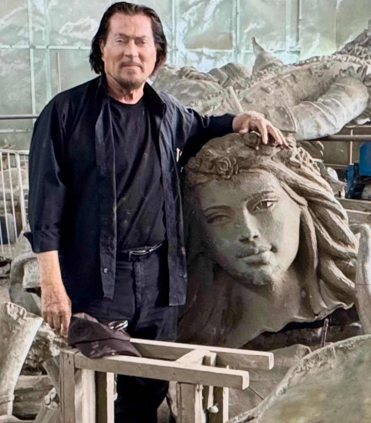 Artist Ginés Serrán-Pagán standing next to a large sculpture of a woman's head.