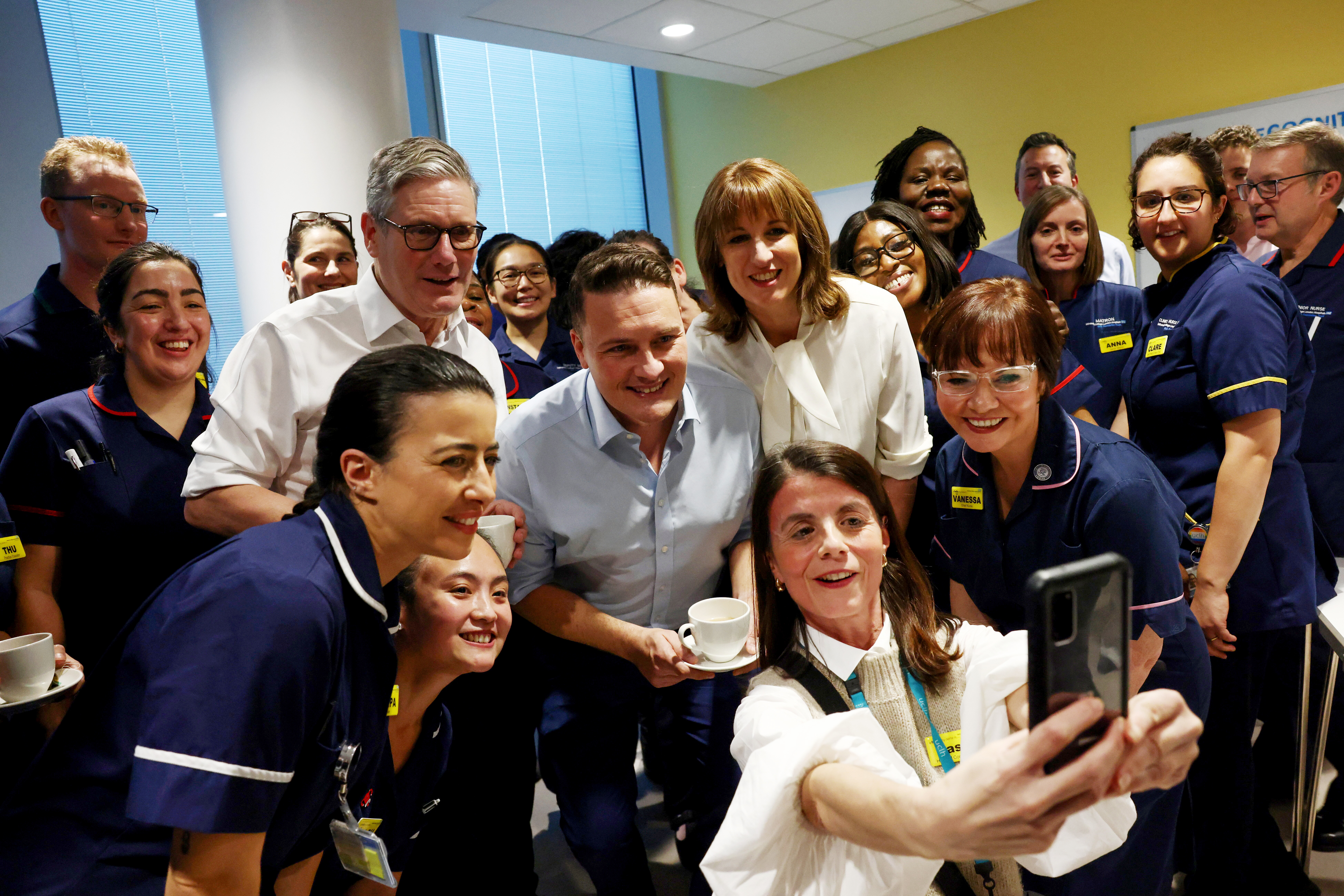 Prime Minister Keir Starmer, Chancellor Rachel Reeves, and Health Secretary Wes Streeting taking a selfie with hospital staff at University College Hospital.