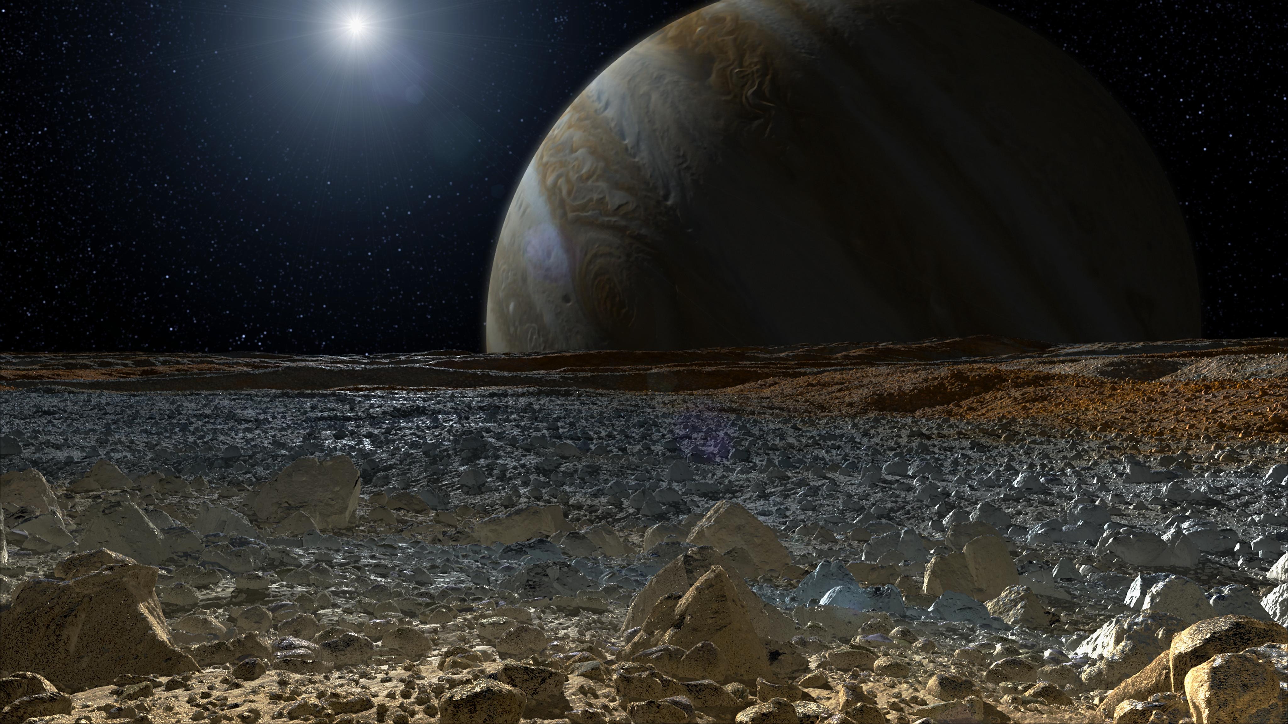 Illustration of a simulated view from the surface of Jupiter's moon Europa, showing its rough, icy surface tinged with reddish areas in the foreground, and the giant planet Jupiter looming over the horizon with a bright star overhead.