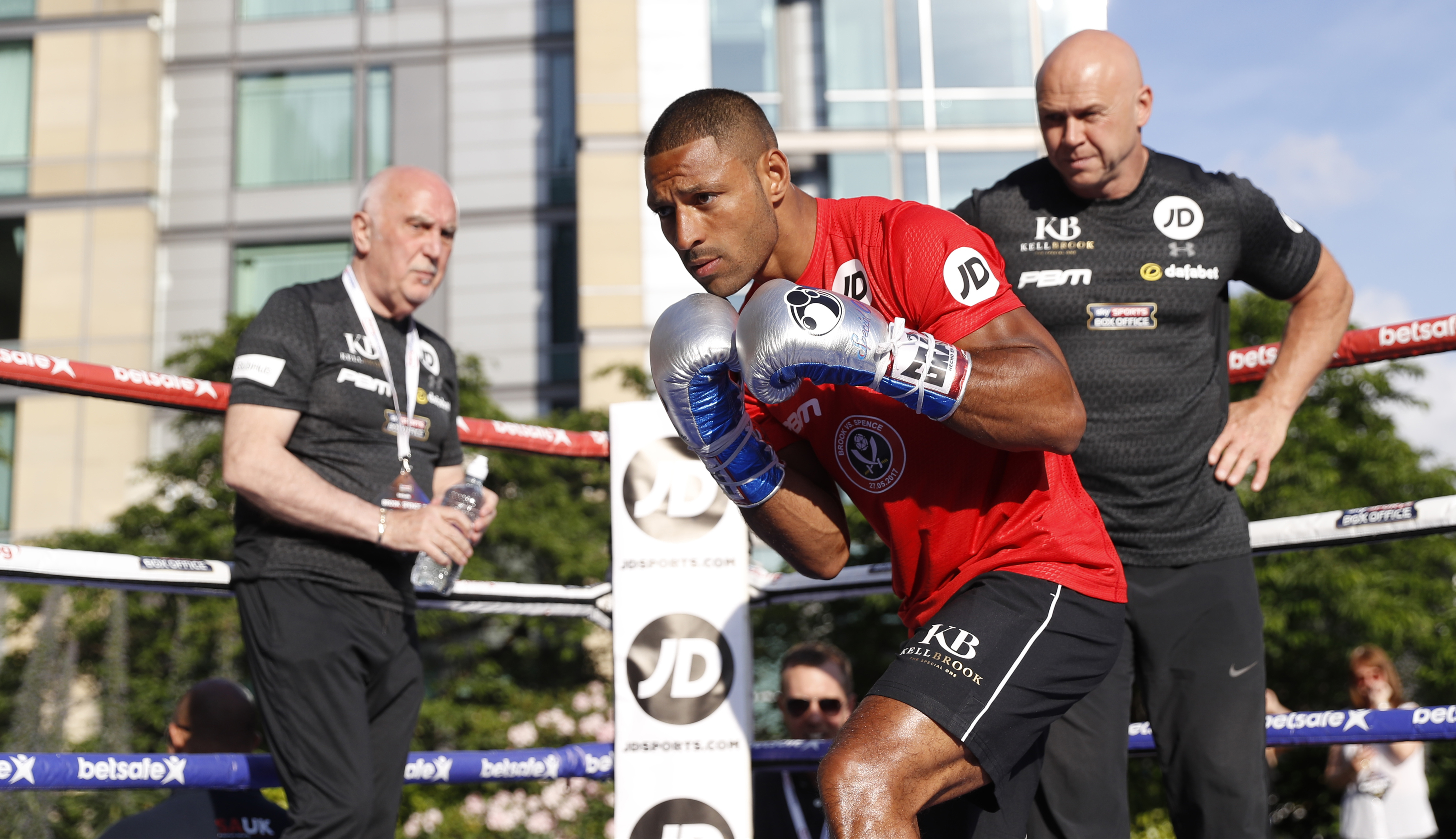 Kell Brook in a red shirt and boxing gloves with trainers Dominic and Brendan Ingle.