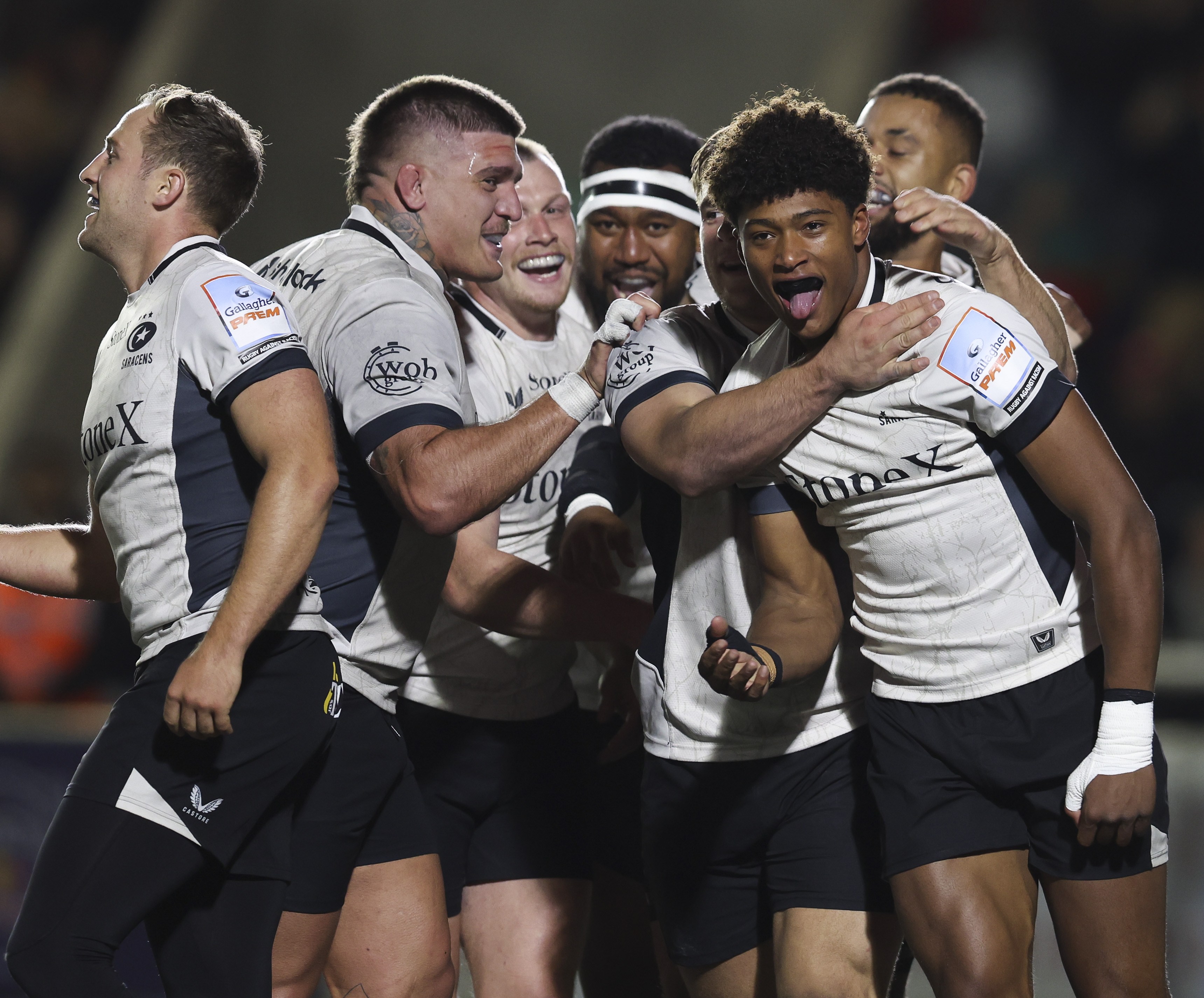 Noah Caluori of Saracens celebrates scoring a try with teammates.