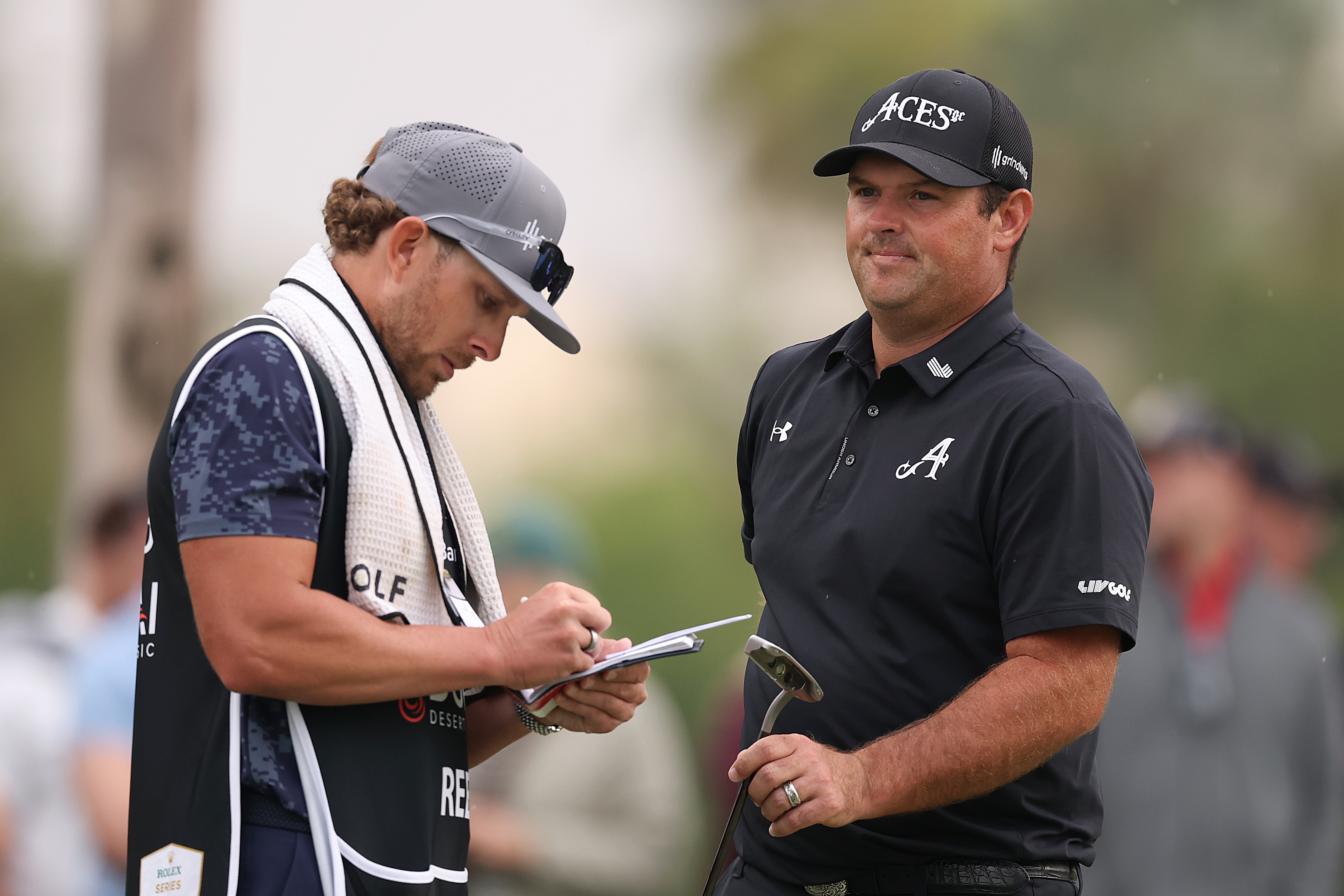 Patrick Reed of the United States interacts with his caddie, Kessler Karain, on the 17th green during day four of the Hero Dubai Desert Classic 2026.